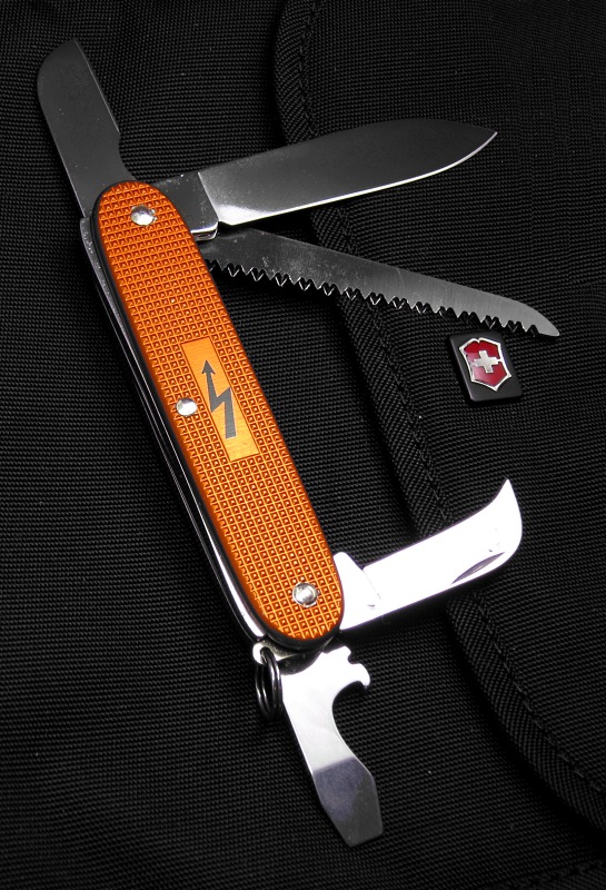 This is a new configuration in a Victorinox 93mm Alox frame.  This knife is part of a short special-run from July 2011 of only 50 pieces.  Each knife is numbered on the small Electrician's/Sheepsfoot blade. The bright Orange (Tangerine) anodized Alox scales are also not very common.  The special electrical symbol in the panel has been seen on only 1 earlier Electrician Solo special.  Apparently there was a mistake during manufacturing and the knives needed to be disassembled and reassembled, This left a few extra marks around the rivets on some knives.  